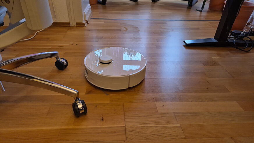 Der Roboter fährt zielsicher durch einen engen Bereich mit mehreren Stuhlbeinen.